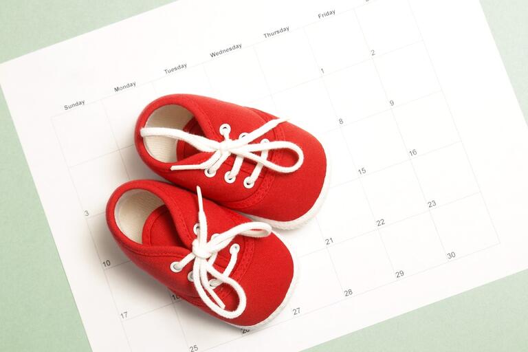 Red baby shoes sitting on a calendar