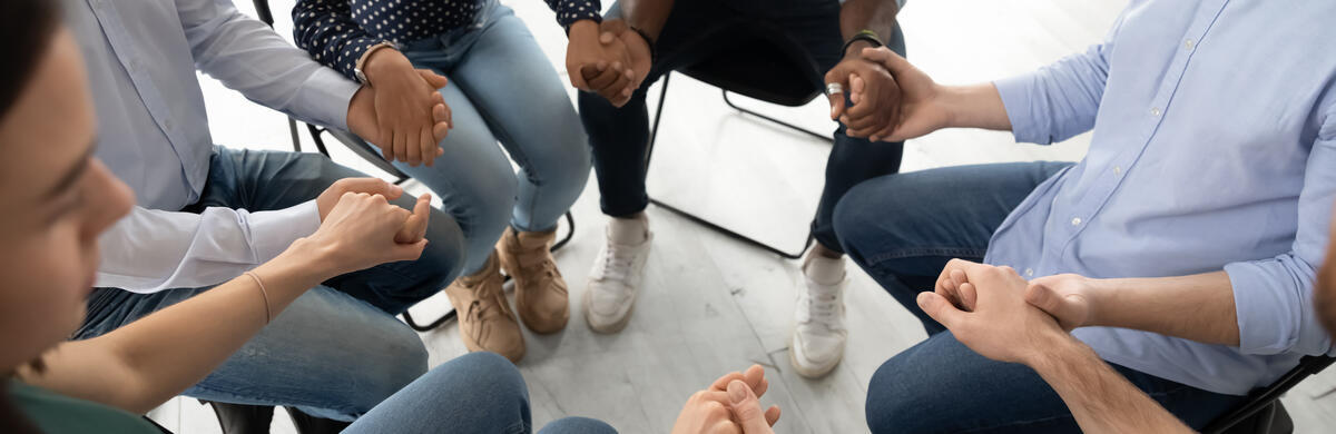 people sitting in a circle and holding hands