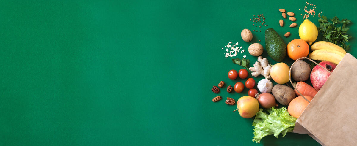 Shopping or delivery healthy food background. Healthy vegan vegetarian food in paper bag vegetables and fruits on green, copy space