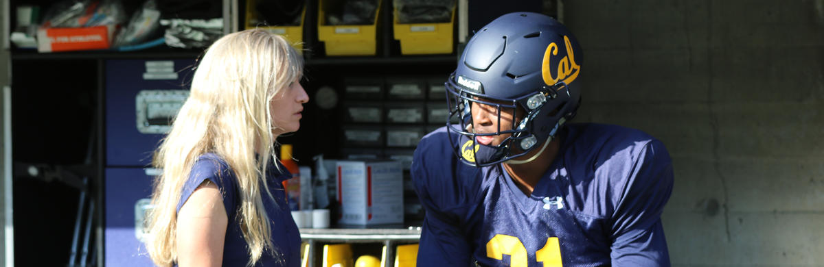 Female sports medicine doctor talking to cal football player