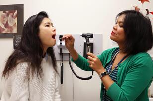 doctor checking student's mouth with light and tongue presser