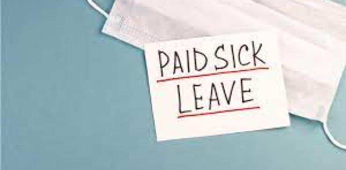 A post-it stuck to a surgical mask that reads 'paid sick leave'
