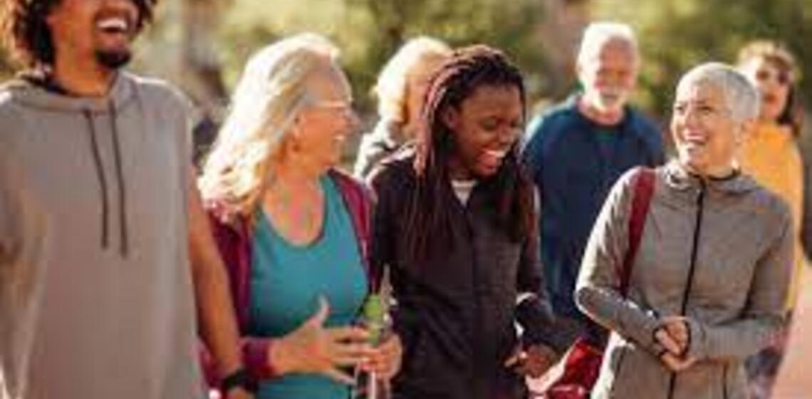 A diverse group of people laughing together as they walk outdoors