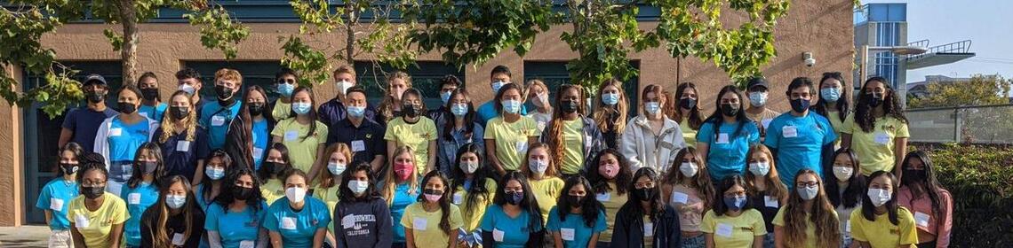 Health workers wearing masks and posing in rows in front of trees at Tang Center