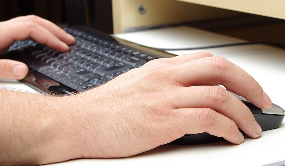 A pair of hands resting on a computer keyboard
