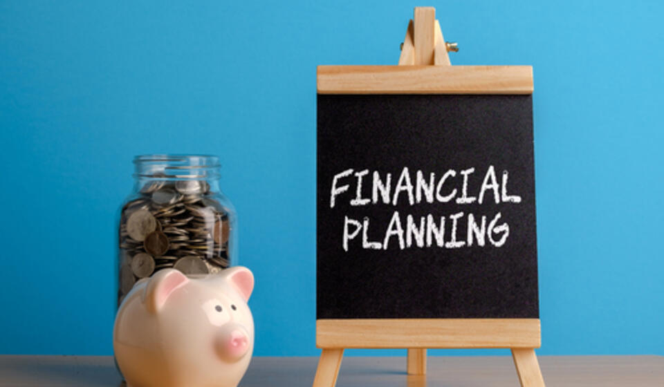 A small chalkboard reading 'Financial Planning' in chalk sits next to a piggy bank filled with coins