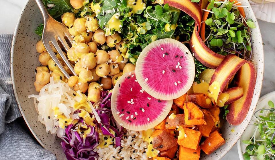 A bowl on a table is filled with bright and colorful vegetables representing plant-based recipes