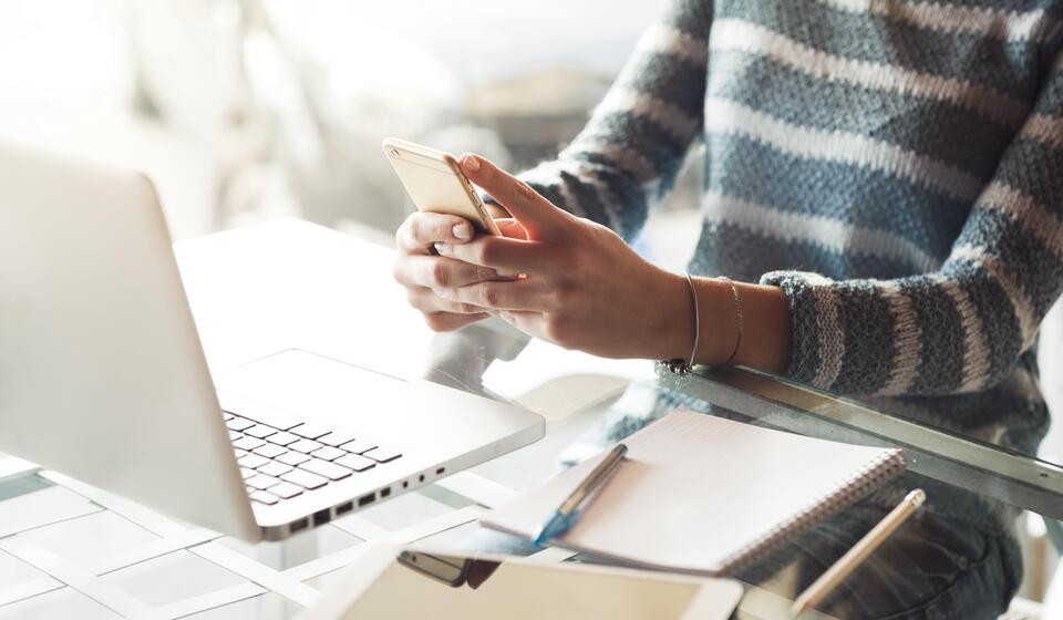 A person sits at a desk looking at a laptop