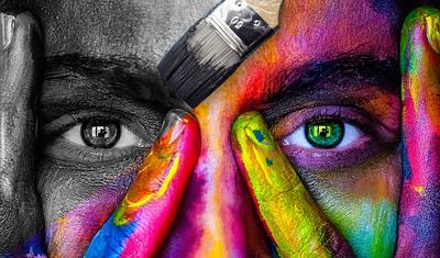 Image of face with colorful paint on one side and black and white on the other