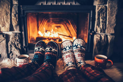 two pairs of feet in wool socks by the fireplace